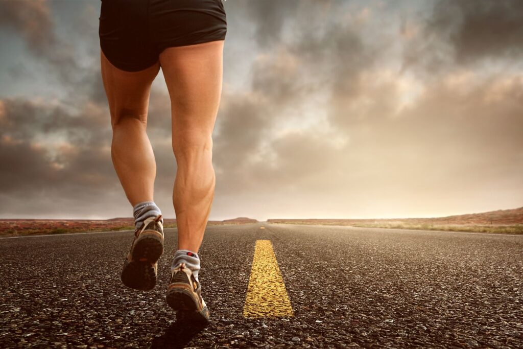 Runner's legs on an open road under a dramatic sky